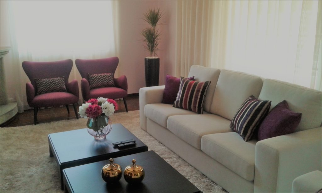 Sala de estar com sofás claros e cadeirões cor de vinho